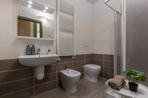 Ein Badezimmer mit Waschbecken, Bidet, Toilette und Duschbereich.
