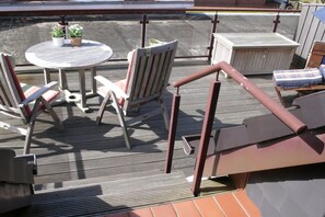 A wooden deck with a round table, chairs, and a hot tub. - Holiday apartment with 1 bedroom (Borkum)