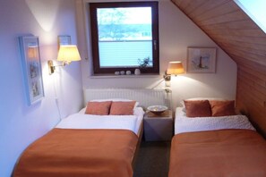A bedroom with two beds, a window, and wall-mounted lamps. - Holiday apartment with 1 bedroom (Borkum)