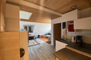 A modern kitchen with a wooden ceiling, a dining area with a table and chairs, and a visible kitchen counter. - Holiday apartment with 1 bedroom (Borkum)