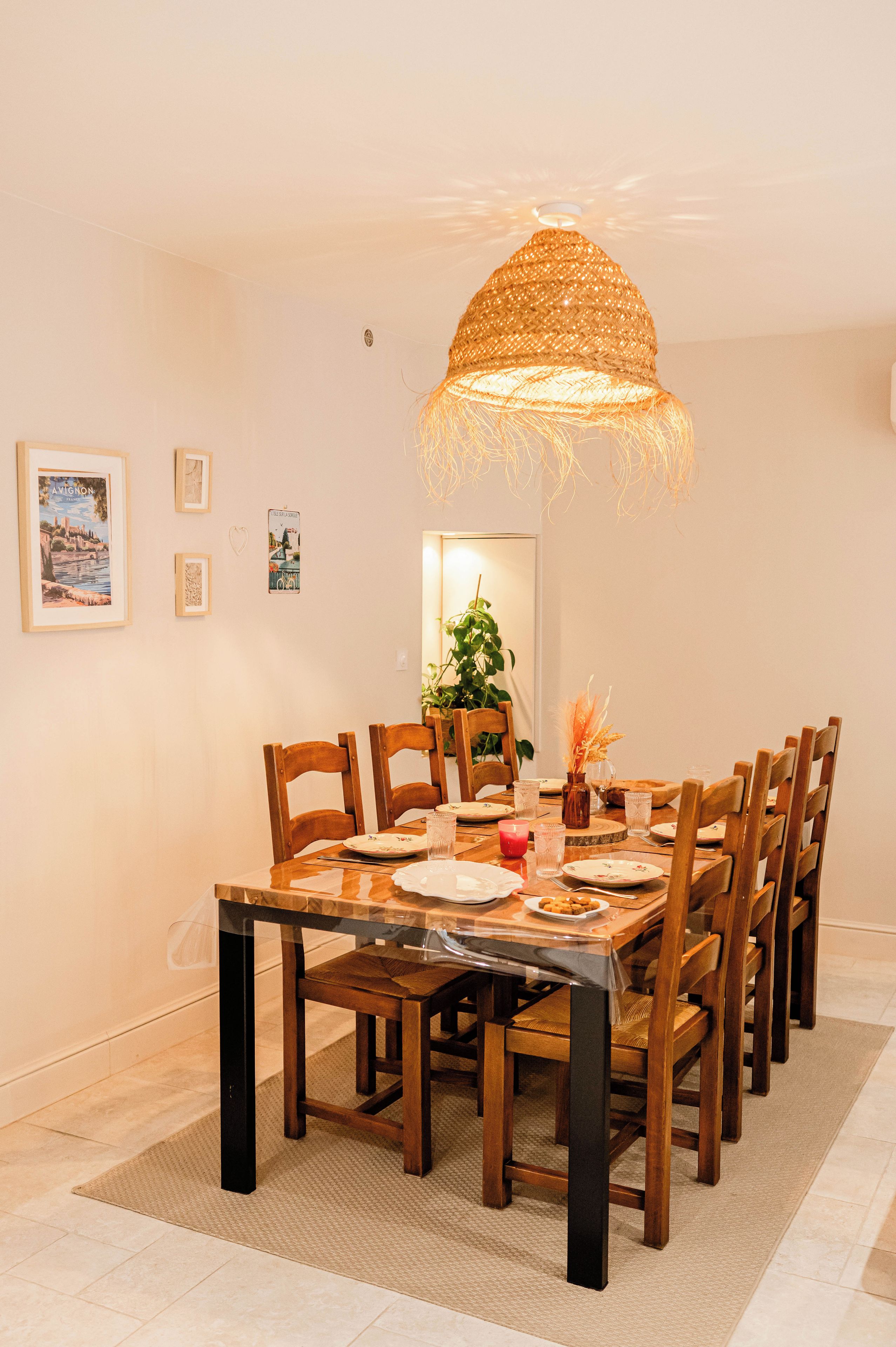 Un espace repas comprenant une grande table en bois, des chaises et un luminaire suspendu.