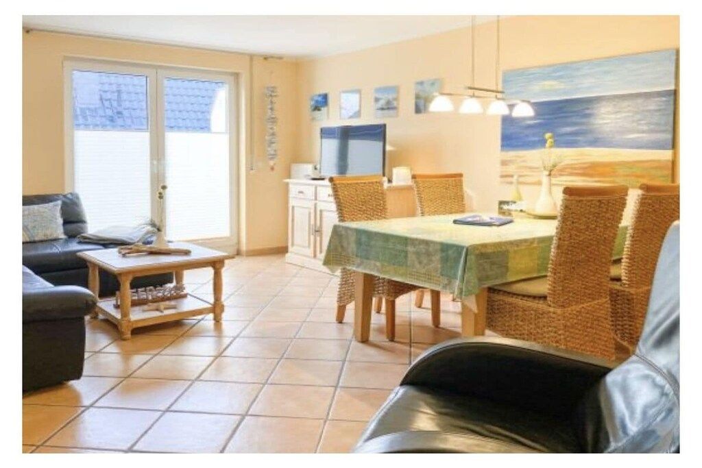Ein Wohnzimmer mit einer Couch, einem Couchtisch, einem Esstisch mit Stühlen und einem Bild an der Wand.