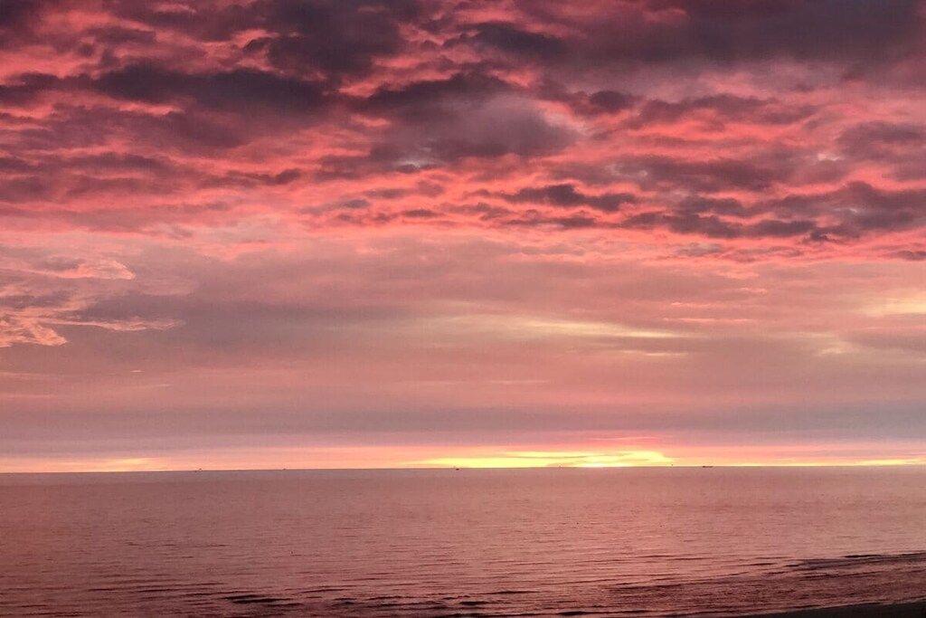 En kustutsikt med en solnedgång över havet.