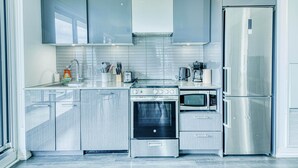 Une cuisine moderne dotée d’appareils électroménagers en acier inoxydable, de meubles de rangement gris et d’un four encastré.