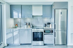 Une cuisine moderne dotée d’appareils électroménagers en acier inoxydable, de meubles de rangement gris et d’un four encastré.