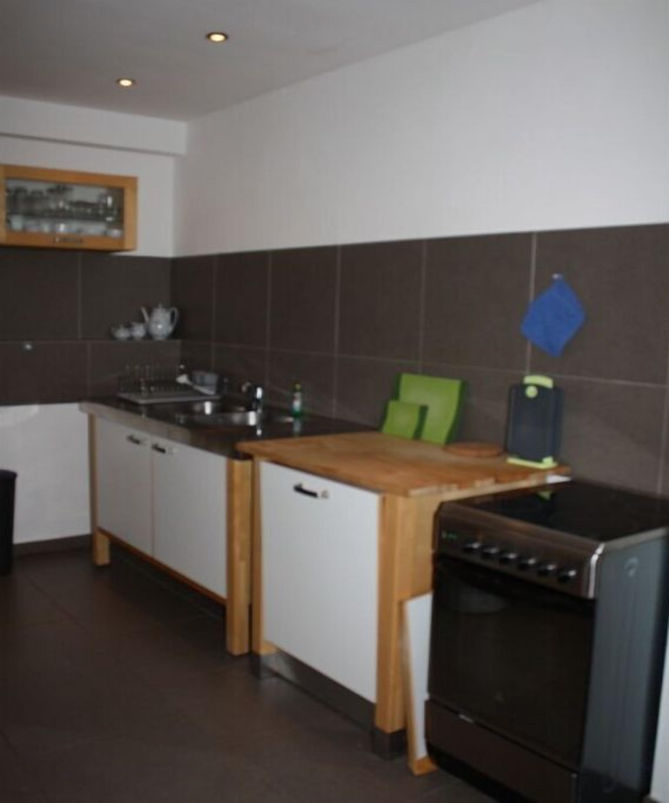 A kitchen with a stove, sink, and cabinets.