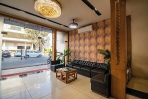 Un hall d’hôtel comprenant un comptoir d’accueil, un canapé, une table basse et une grande fenêtre donnant sur la rue.