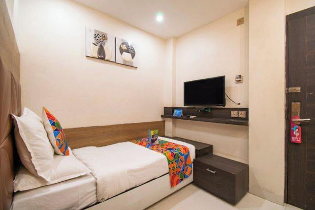 A hotel room with a bed, a TV, a small desk, and a door.