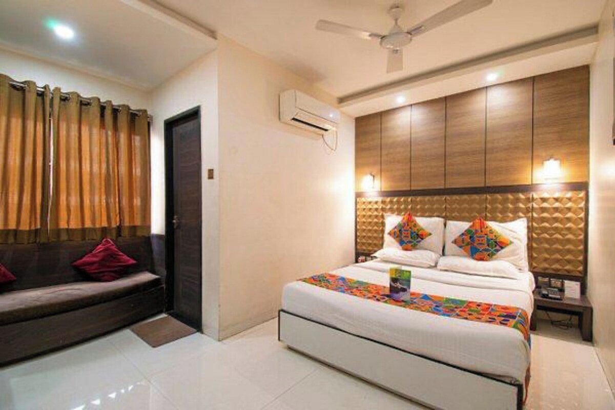 A hotel room with a bed, a sofa, a ceiling fan, and a nightstand.