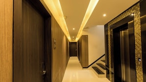 Un couloir d’hôtel moderne avec des portes en bois, un escalier et un ascenseur.