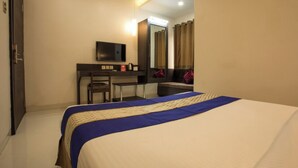 Une chambre d’hôtel avec un lit, un bureau, une télévision et un miroir.