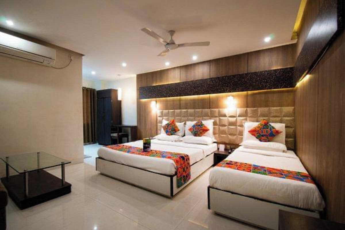 A hotel room with two beds, a ceiling fan, and a glass table.