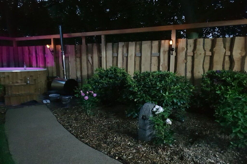 Ein Holzzaun, eine Holzbank und ein Gartenbereich mit Mulch und Pflanzen.