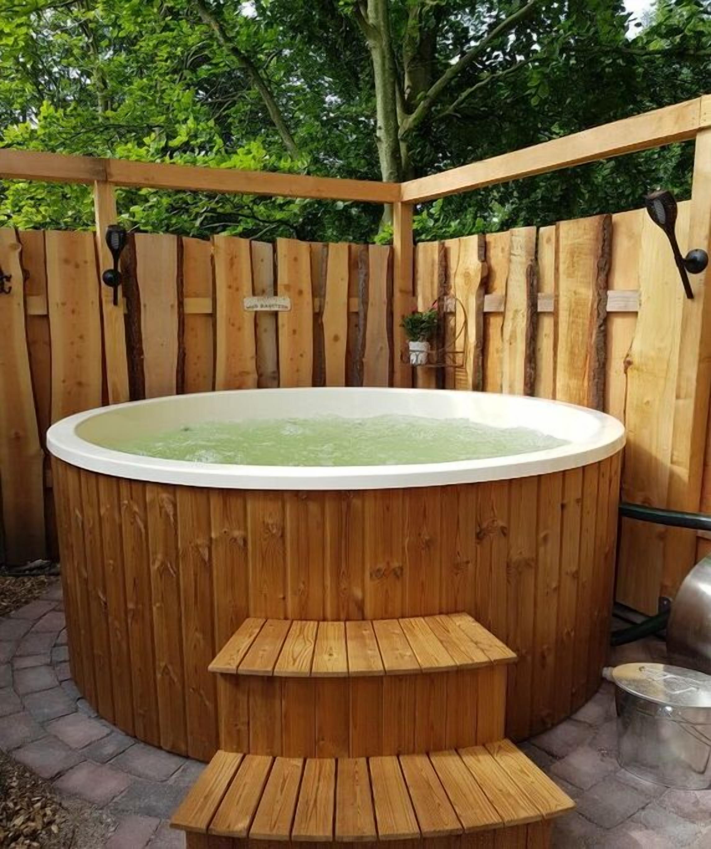 A hot tub with a wooden deck and steps, surrounded by a wooden fence.