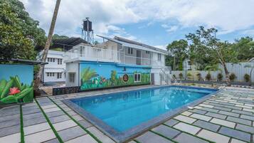 A swimming pool with a mural, a white building, and a water tower.