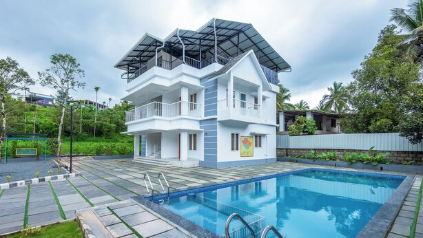 Un edificio moderno a due piani con una piscina di fronte.