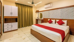 Una camera d'albergo con un letto, un armadio, una ventola a soffitto, un condizionatore d'aria e una finestra con tende.