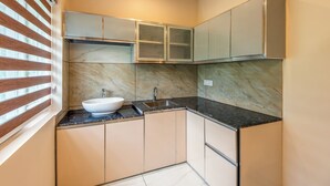 Una cucina compatta con lavandino bianco, piano di lavoro scuro e mobili beige.