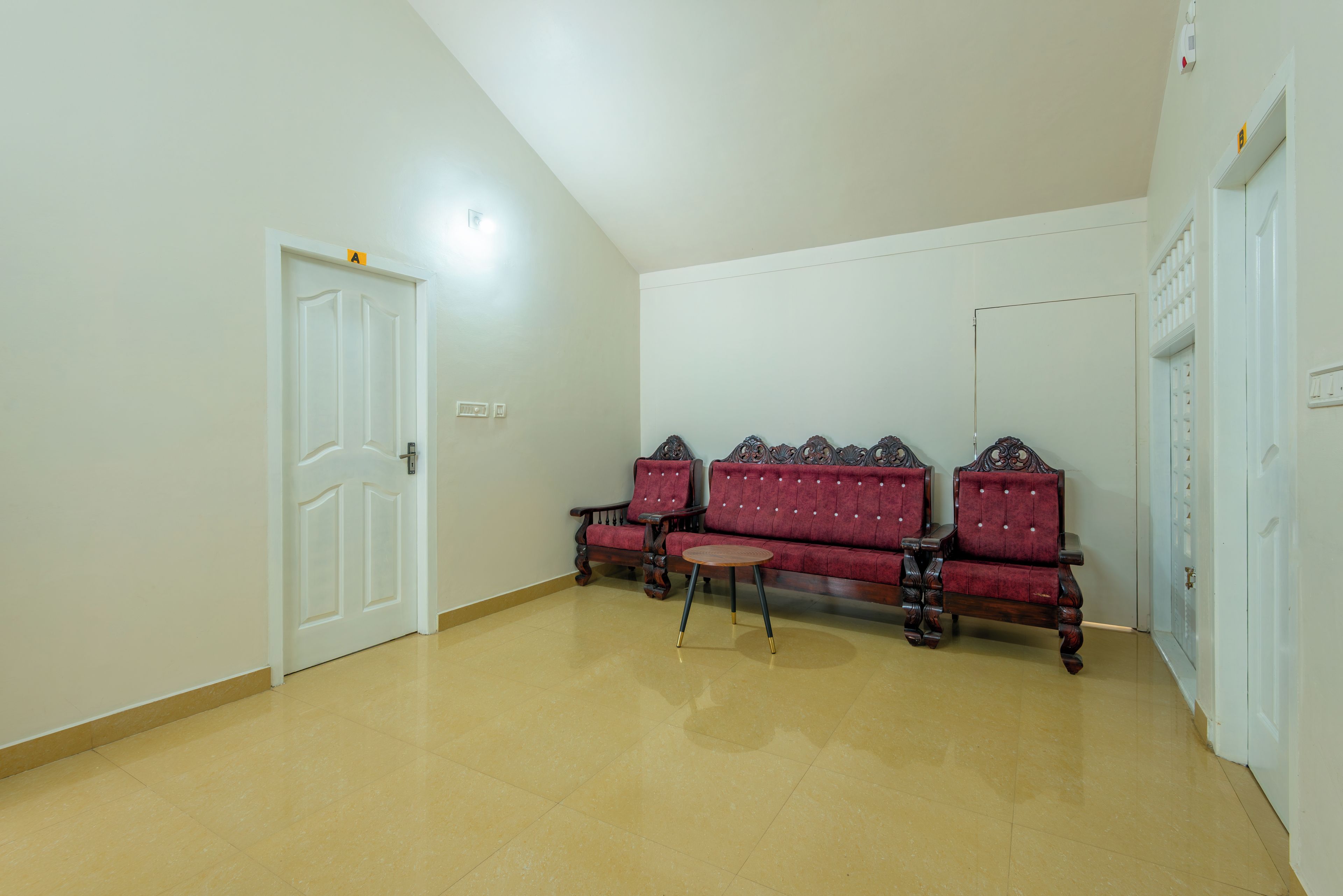 A room with a white door, a red upholstered sofa, and a small wooden table.