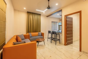 Uma sala de estar moderna com um conjunto de sofás, uma mesa de centro e uma área de jantar com cadeiras.