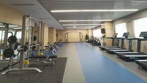 A gym with exercise equipment, treadmills, and a blue floor. - Grand Skylight X-INN Inn Pingshan (Shenzhen)