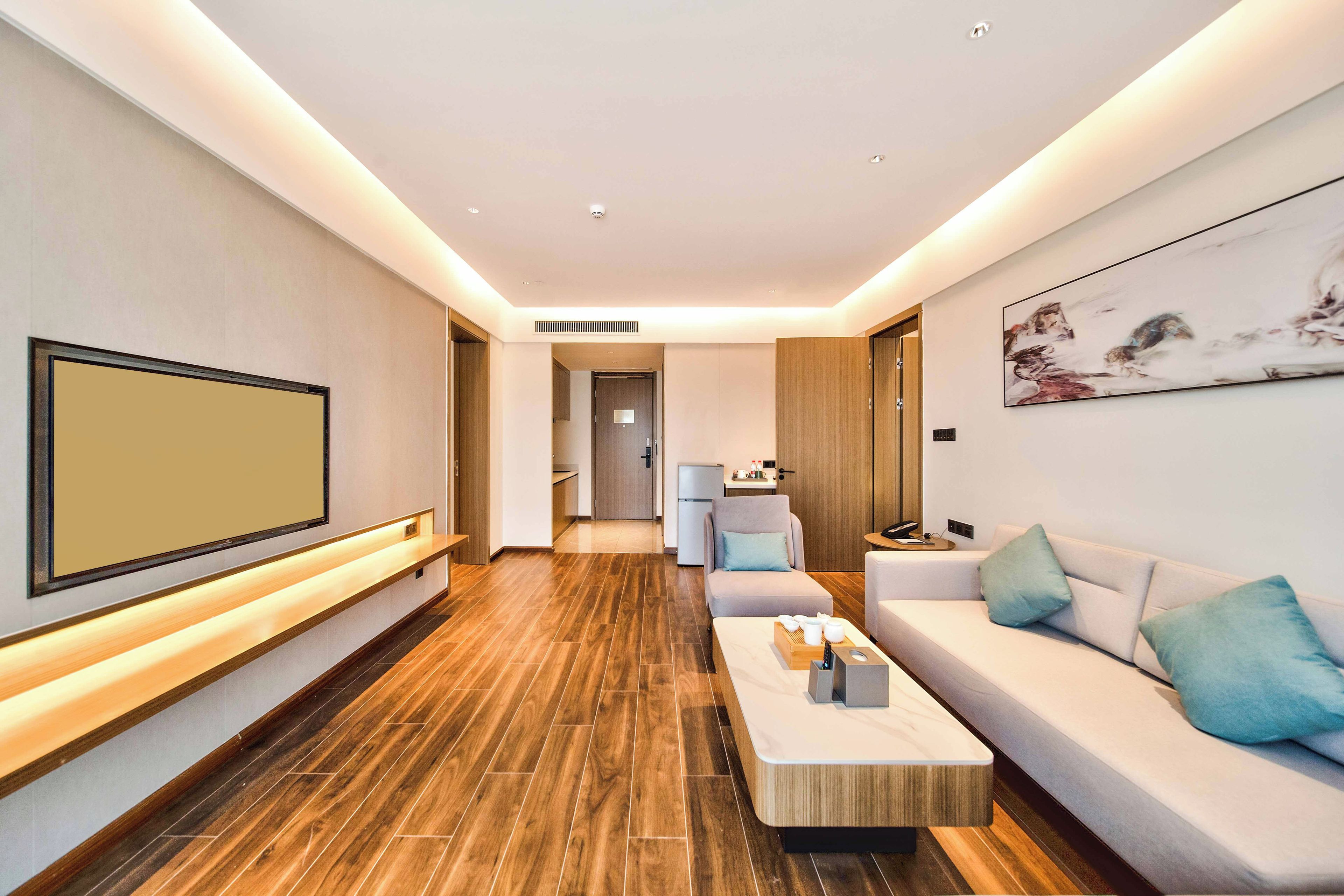 Una sala de estar moderna con un televisor de pantalla plana grande, un sofá, una mesita de centro y un cuadro en la pared.