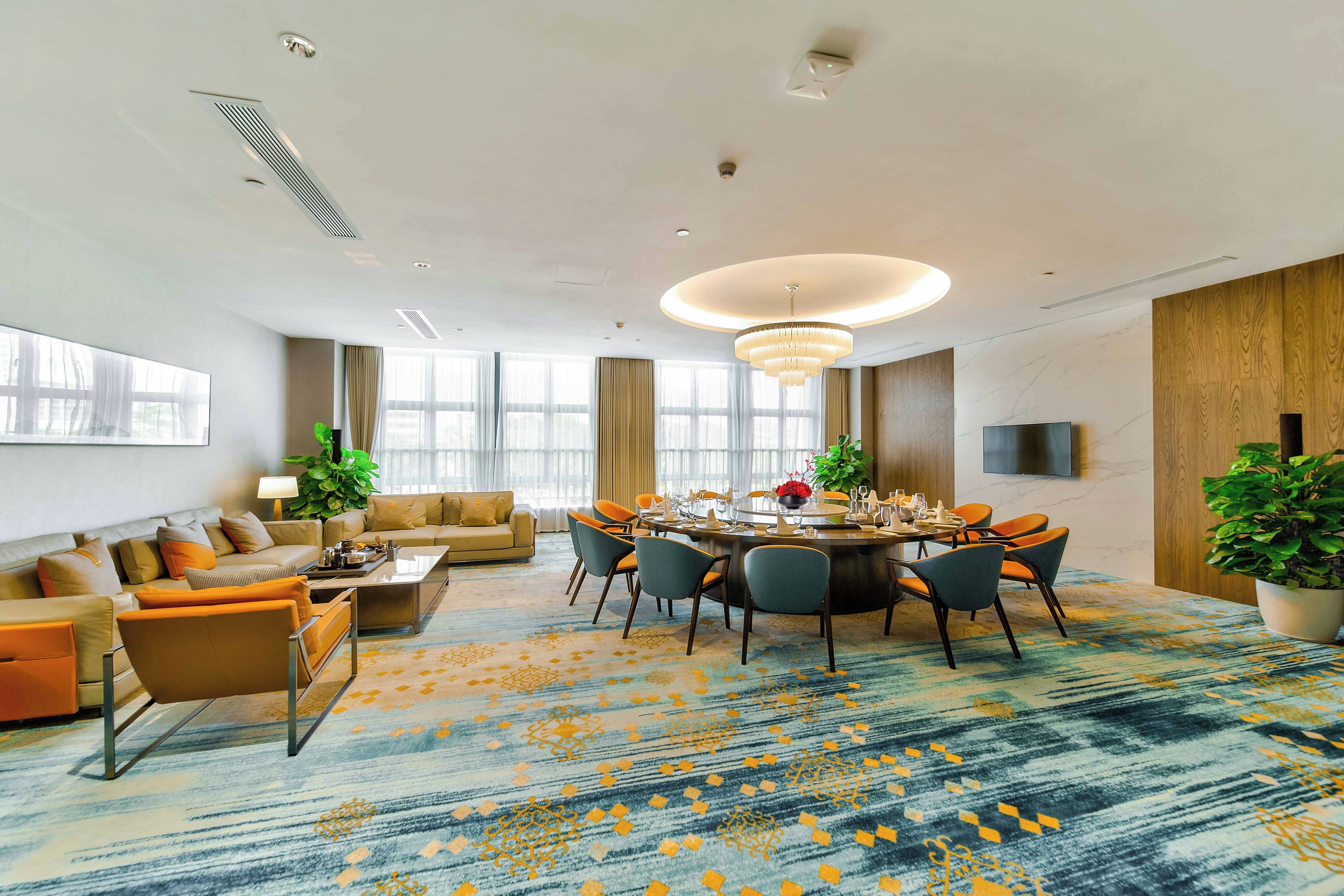 Una habitación de hotel moderna con zona de comedor, un conjunto de sofás y un amplio ventanal.