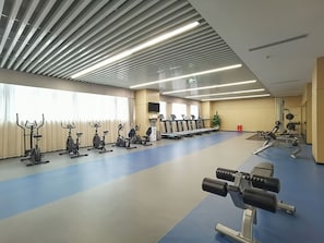 A gym with exercise equipment, a blue floor, and a sloped ceiling.