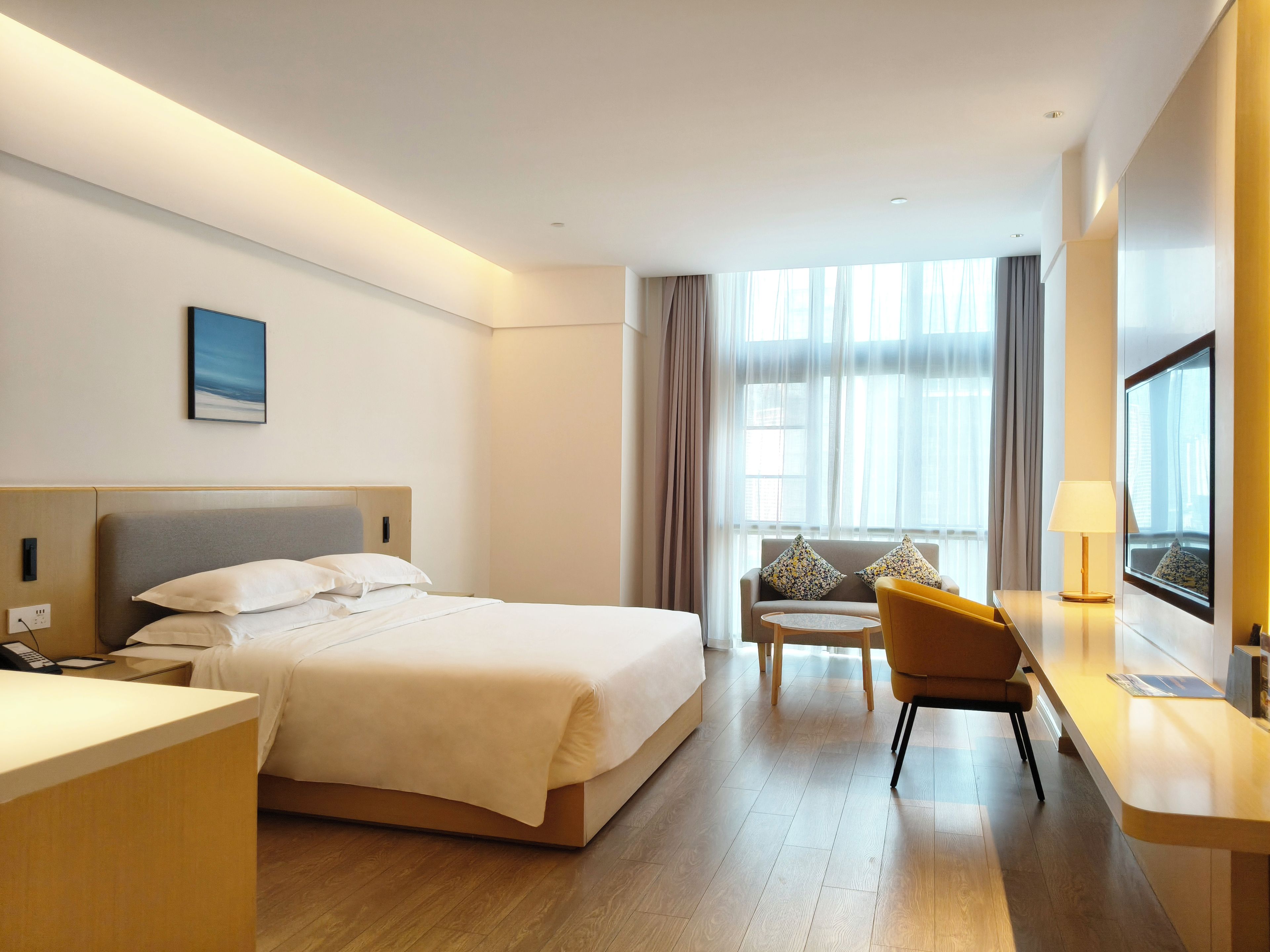 Une chambre d’hôtel avec un lit, un bureau, une chaise et une fenêtre avec des rideaux.