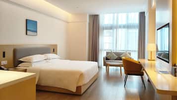Une chambre d’hôtel avec un lit, un bureau, une chaise et une fenêtre avec des rideaux.