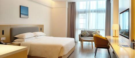 A hotel room with a bed, a desk, a chair, and a window with curtains.