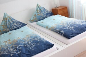 A bed with floral patterned bedding and a wooden nightstand beside it. - Holiday home with 1 bedroom (Bodenwerder)