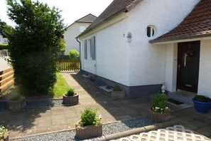 Ein Wohnhaus mit befestigter Auffahrt, Holzzaun und Kübelpflanzen.