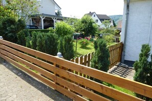 A wooden fence with a garden in the background. - Holiday home with 1 bedroom (Bodenwerder)