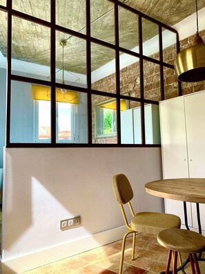 Una habitación con un ventanal grande, una silla, una mesa y un armario.