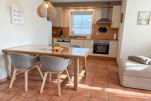 Een kleine keuken met een eettafel, stoelen en een bank.