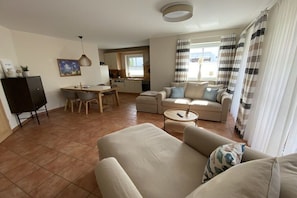 Een woonkamer met een bank, een salontafel en een eethoek met stoelen en een tafel.