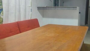 Una habitación con una mesa de madera, un sofá rojo y un armario blanco.