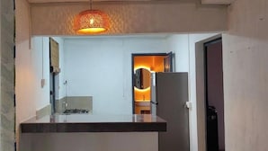 Una cocina de diseño moderno, con una lámpara colgante y vistas al área de comedor contigua.