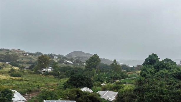 Paisaje rural con casas dispersas y vegetación densa.