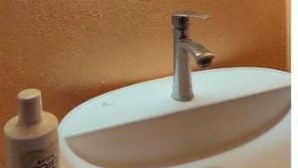 Un baño con un espejo redondo, un lavamanos y una botella de jabón para manos.