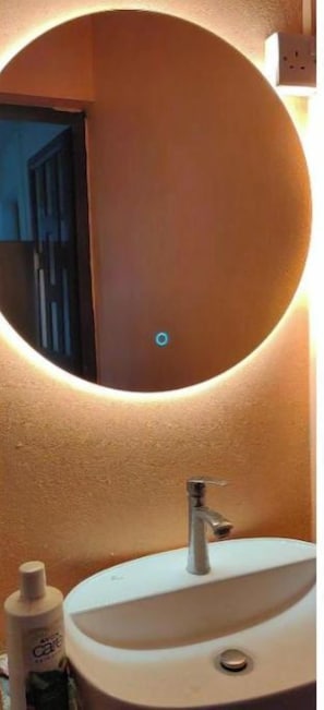 A bathroom with a round mirror, a sink, and a bottle of hand soap. - Henz and Sia Tourist Residence 2 — Your Peaceful Island Home in Rodrigues (Reposoir)