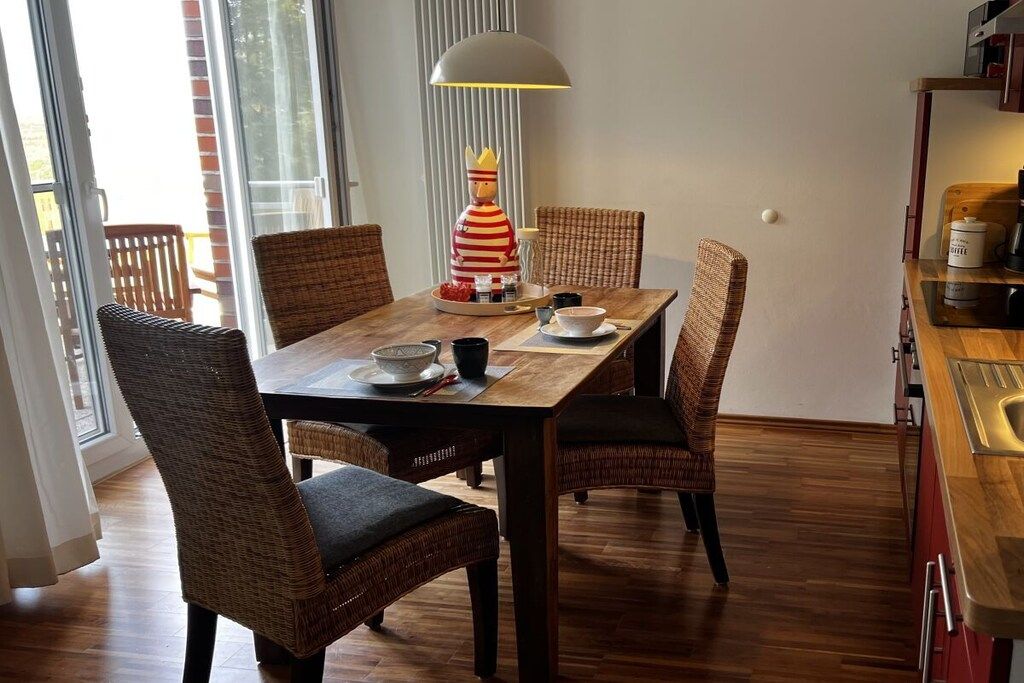 A dining area with a wooden table, wicker chairs, and a decorative lamp.