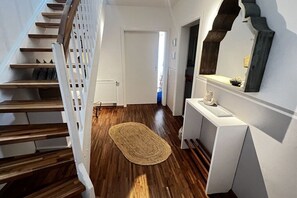 Eine Treppe mit hölzernen Stufen und einem weißen Geländer, die zu einem Raum mit einer weißen Tür und einer dunkelholzvertäfelten Wand führt.
