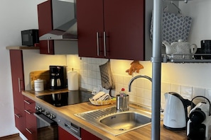 Een moderne keuken met roestvrijstalen apparatuur, een koffiezetapparaat, een waterkoker en een magnetron.