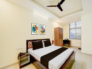 A hotel room with a bed, a wardrobe, a desk, and a window.