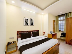 A hotel room with a bed, bedside table, lamp, and a window with curtains.