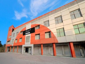 A multi-story building with a prominent orange and white facade, a large sign reading 'Collection,' and multiple closed shuttered storefronts at the ground level.