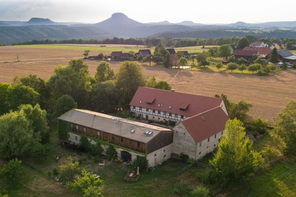 Ein ländliches Anwesen mit einem großen Scheunengebäude, einem Bauernhaus und umliegenden Feldern.