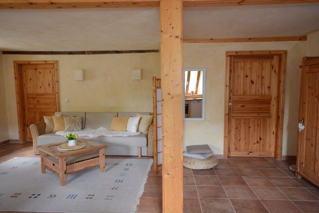 Ein Zimmer mit Holzboden, einer Couch, einem Couchtisch und einer Tür.